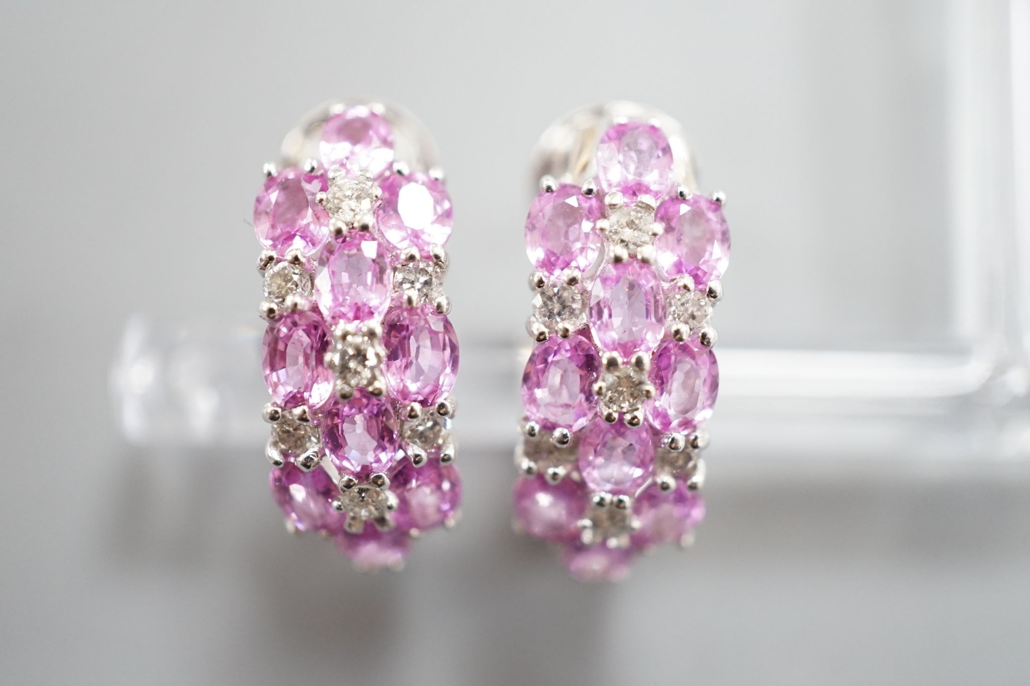 A modern pair of 14k white metal, pink sapphire and diamond cluster set half hoop earrings, 17mm, gross weight 8.3 grams.